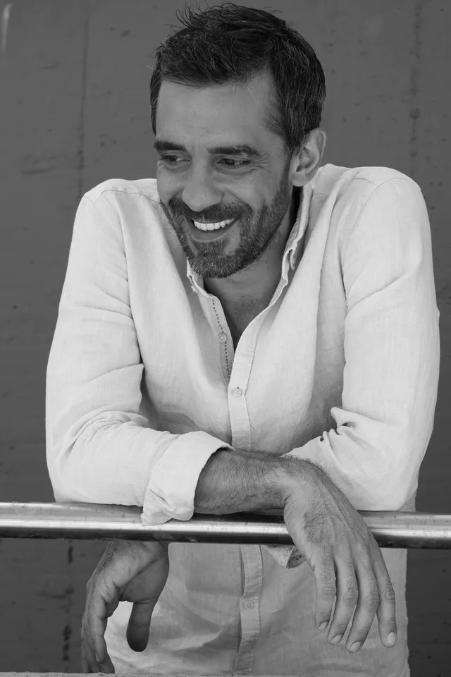 Ritratto in bianco e nero di Marco Bellocchio, sorridente, appoggiato a una ringhiera